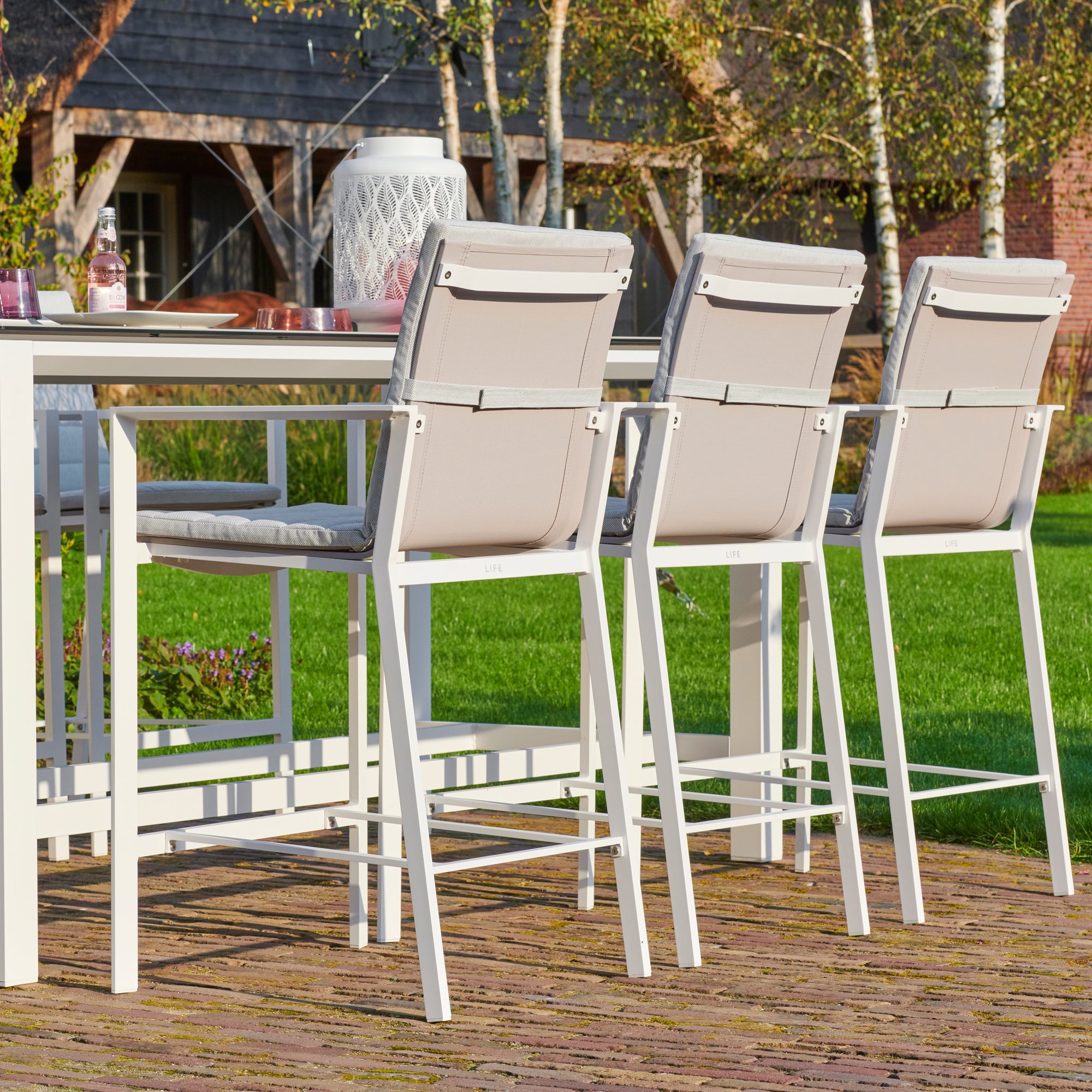 Primavera 7-Piece Bar Set - White  in a beautiful outdoor patio setting shows a close up of the back of the slinged chair with cushion