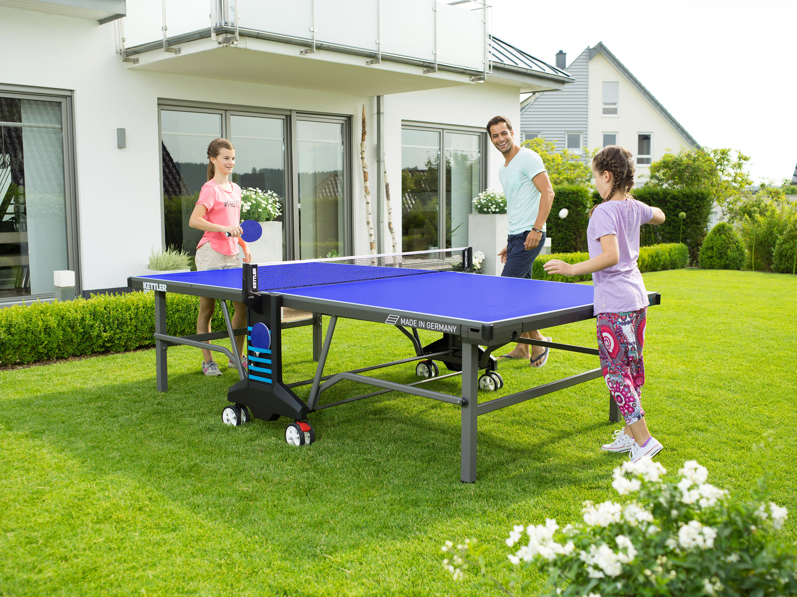 Family plays outdoor table tennis on Kettler Outdoor Table Tennis Table 